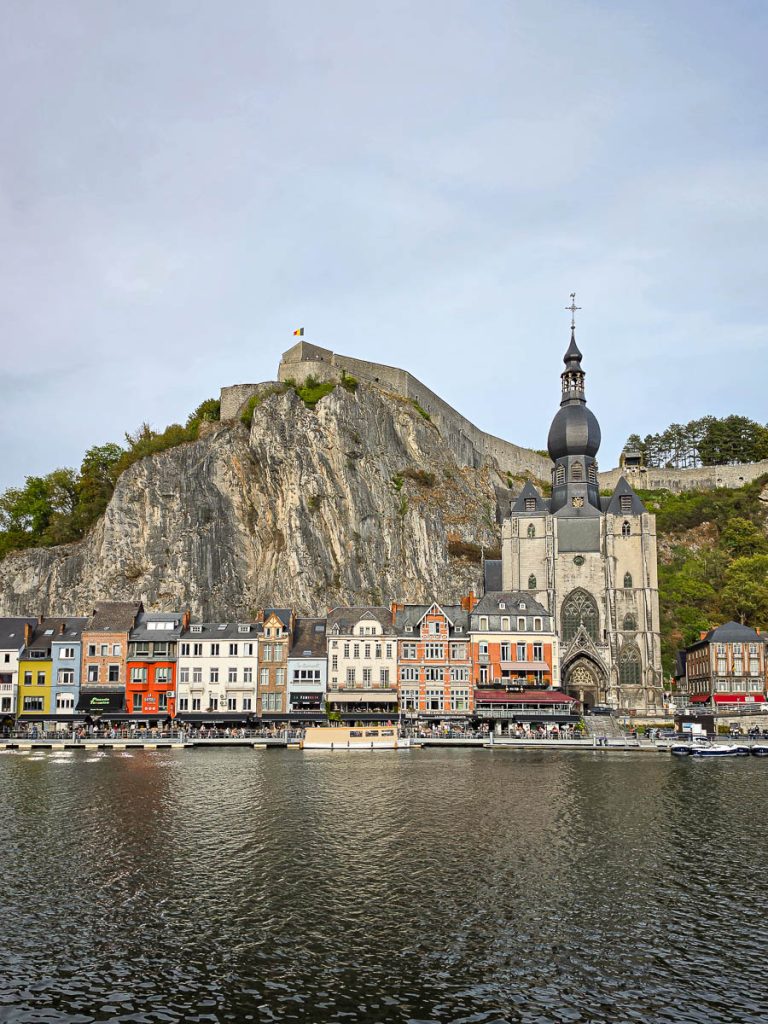 Collegiata di Notre-Dame a Dinant con il campanile a bulbo sotto la parete rocciosa e la Mosa